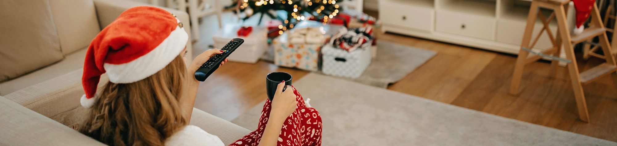 Woman wearing a santa hat watching TV