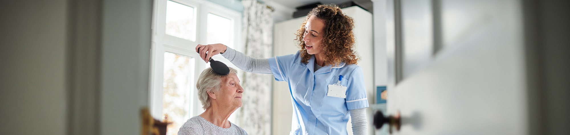 Young woman brushing older woman's hair